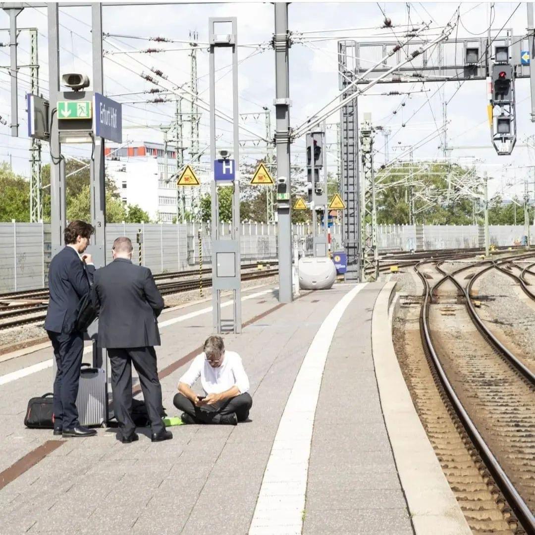 Minister Habeck am Bahnsteig Erfurt Hbf, In Hemd und Anzugshose wartend auf dem Boden des Bahnsteig sitzend.